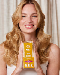 model holding the packaging of Golden Hue hair, plant-based hair color by khadi